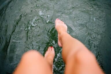 A woman's feet about to hit water, evoking a sense of playfulness.