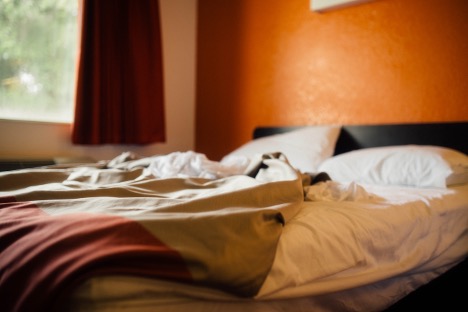 A rumpled bed with a messed-up white sheet and blanket, illustrating the connection between sleep and depression